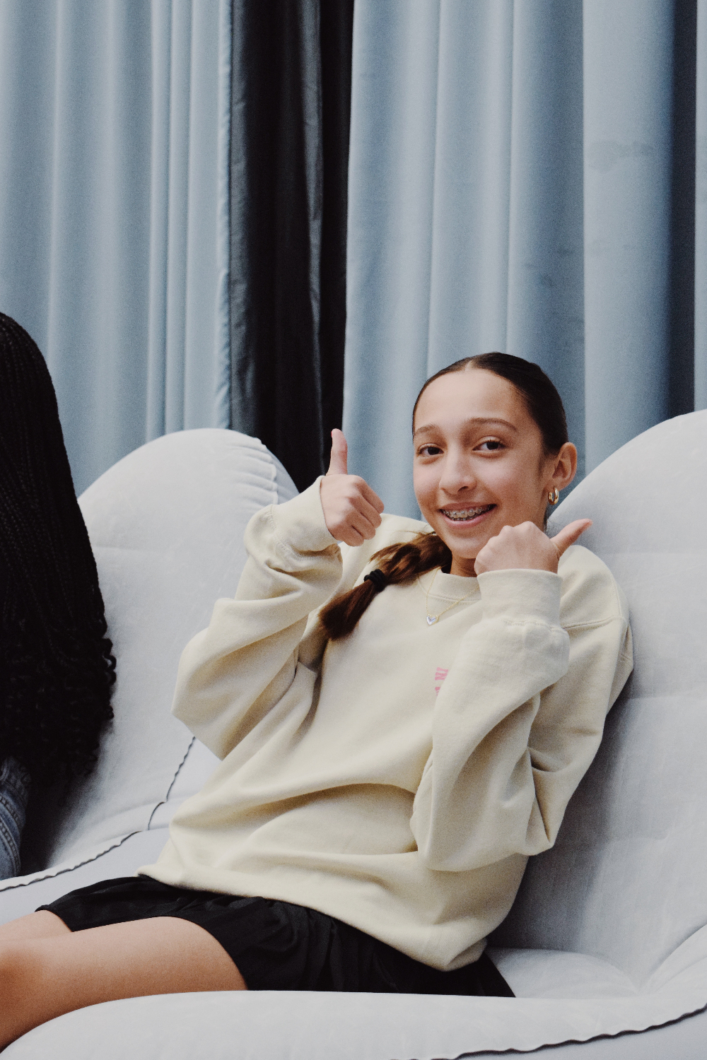 girl sitting on couch giving thumbs up