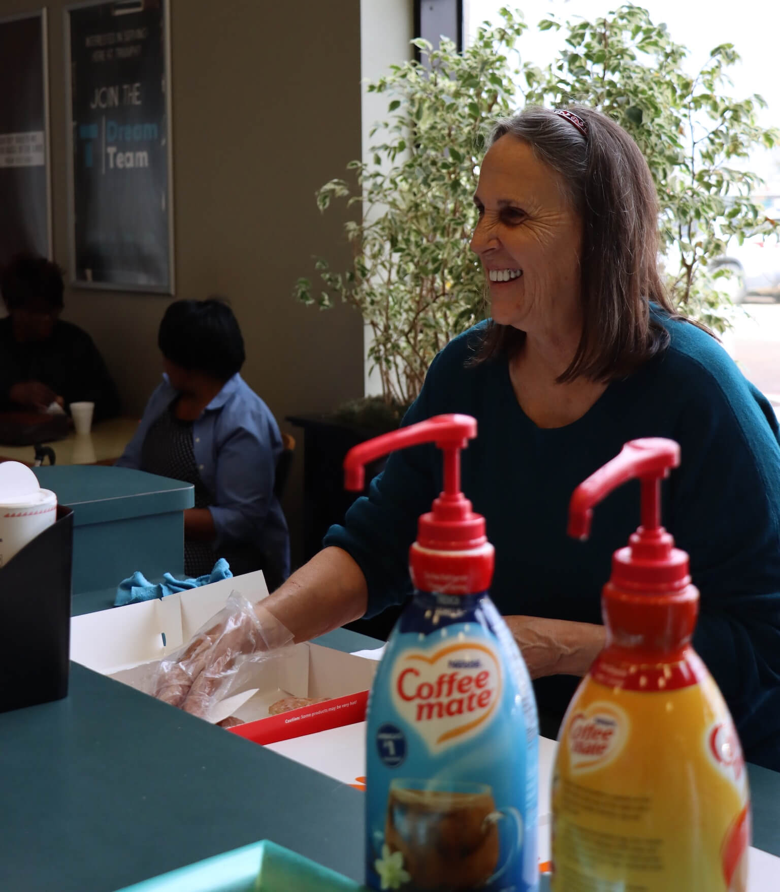 woman serving food with coffee creamer in foreground