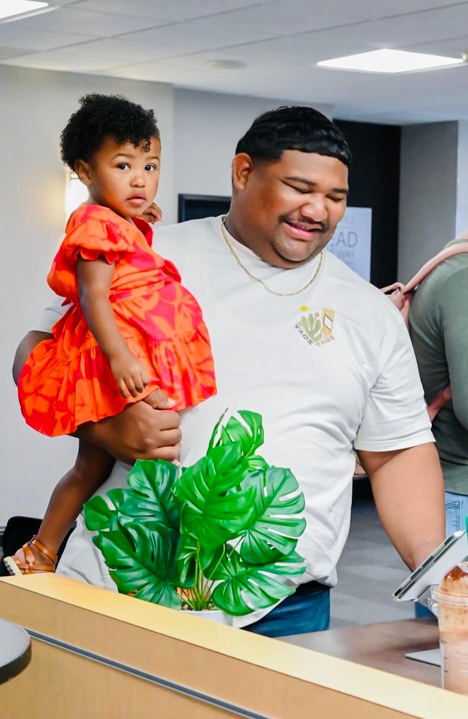 father holding daughter wearing orange dress