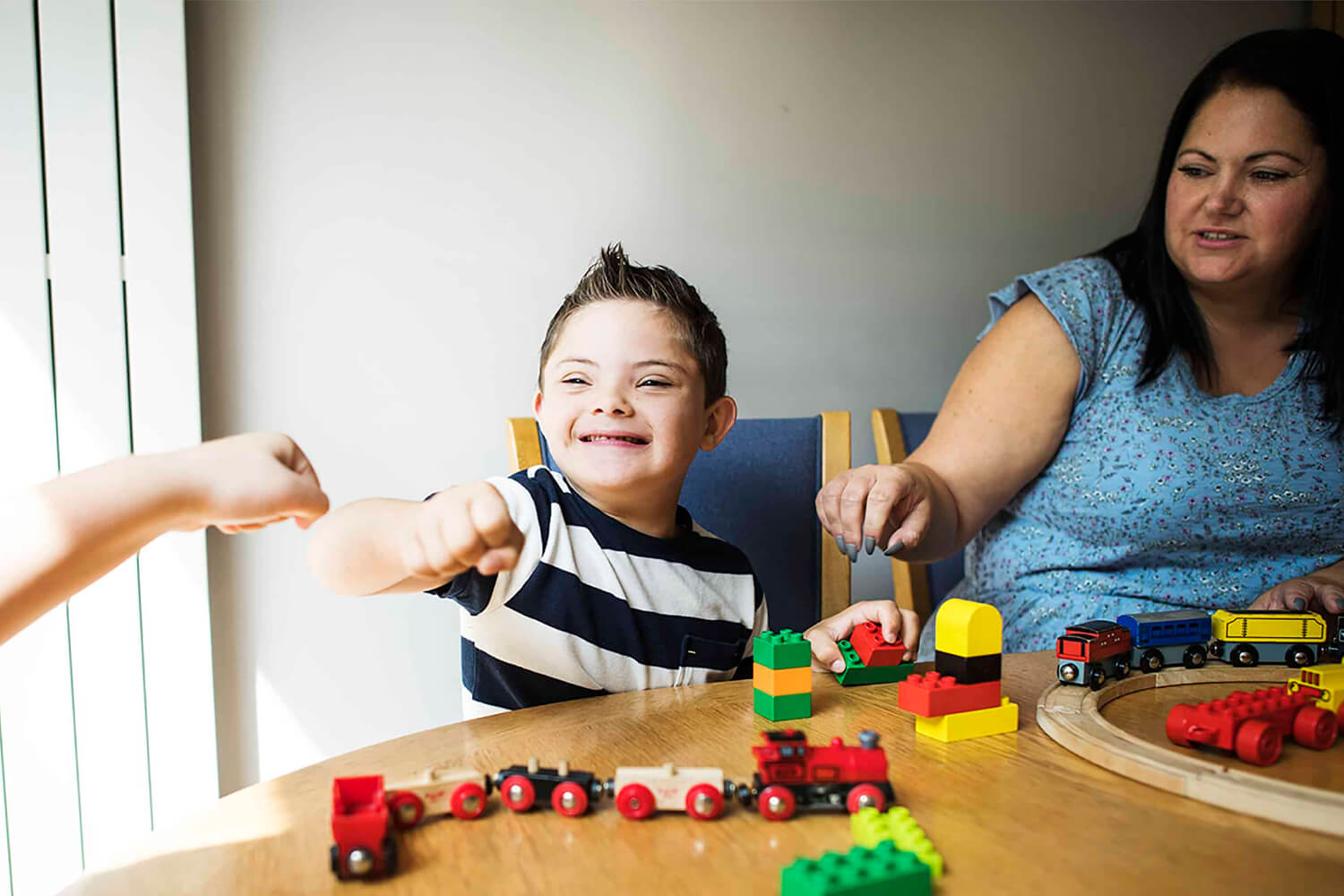 child with building blocks giving fist bump to adult