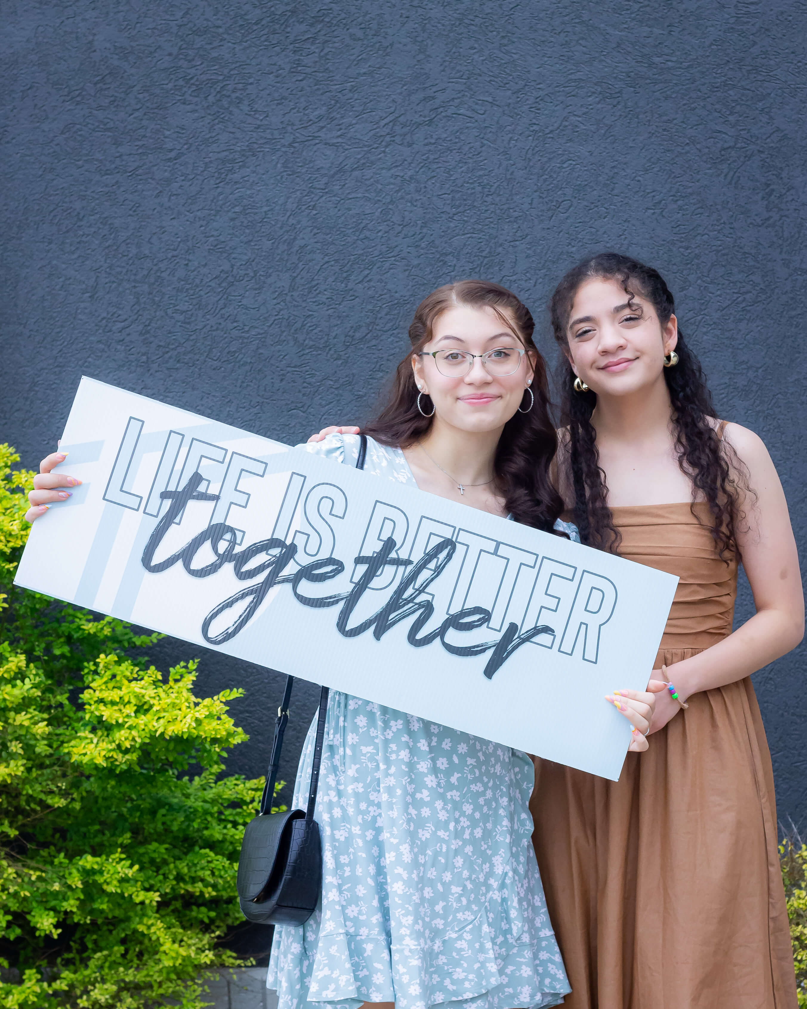 two women holding sign saying life is better together